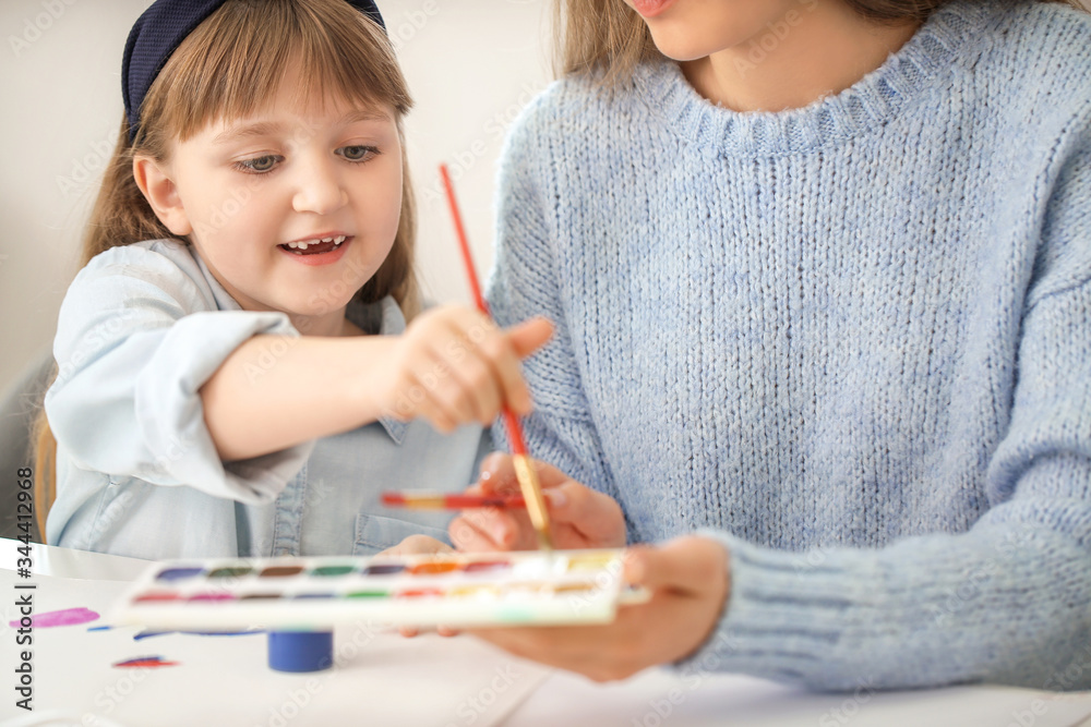 Drawing teacher giving private art lessons to little girl at home