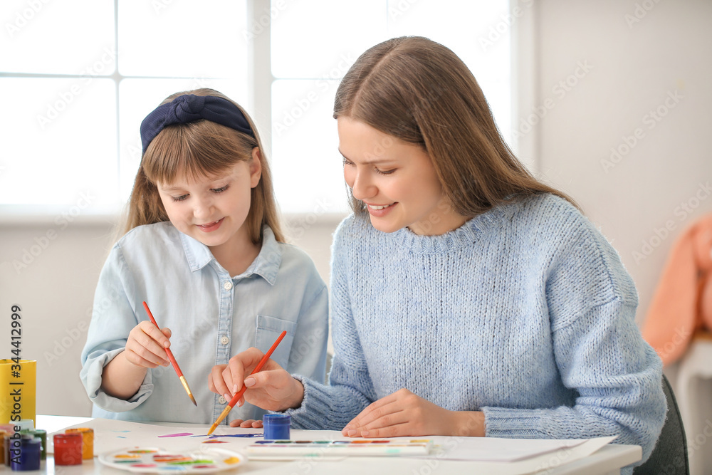 Drawing teacher giving private art lessons to little girl at home