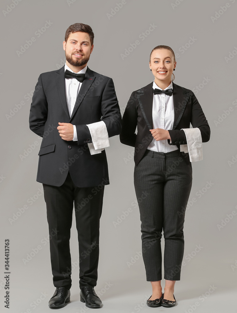 Male and female waiters on grey background