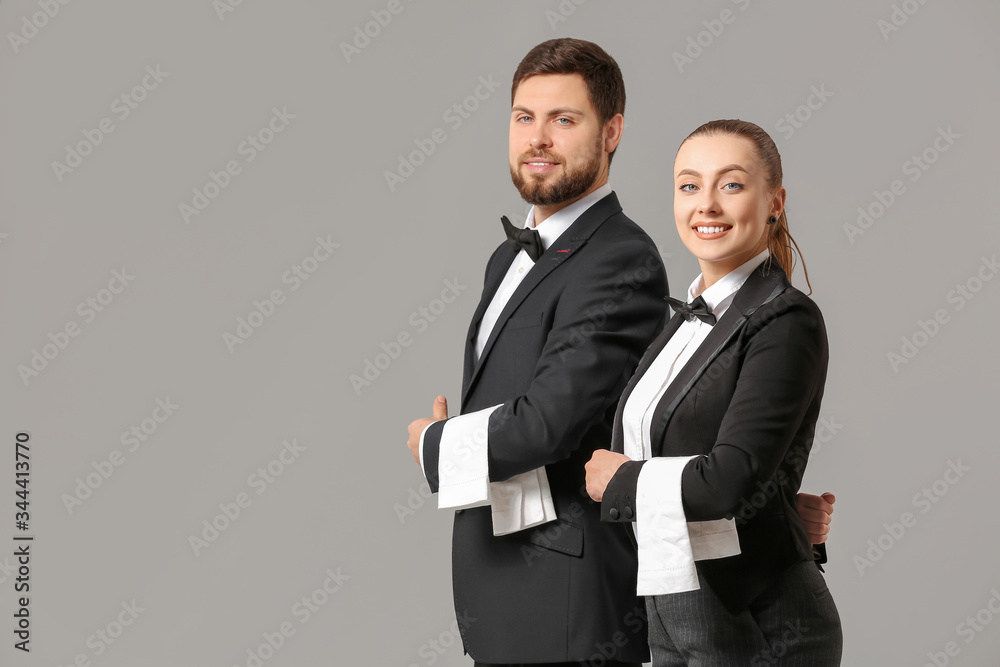 Male and female waiters on grey background