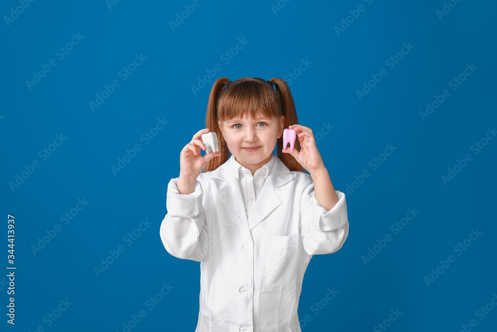 Little dentist with plastic teeth models on color background