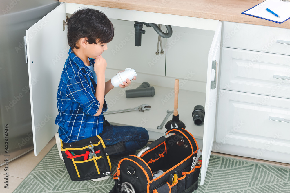 Little plumber repairing sink in kitchen