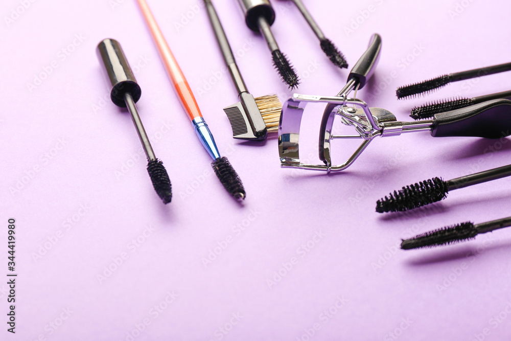 Mascara and eyelash curler on color background