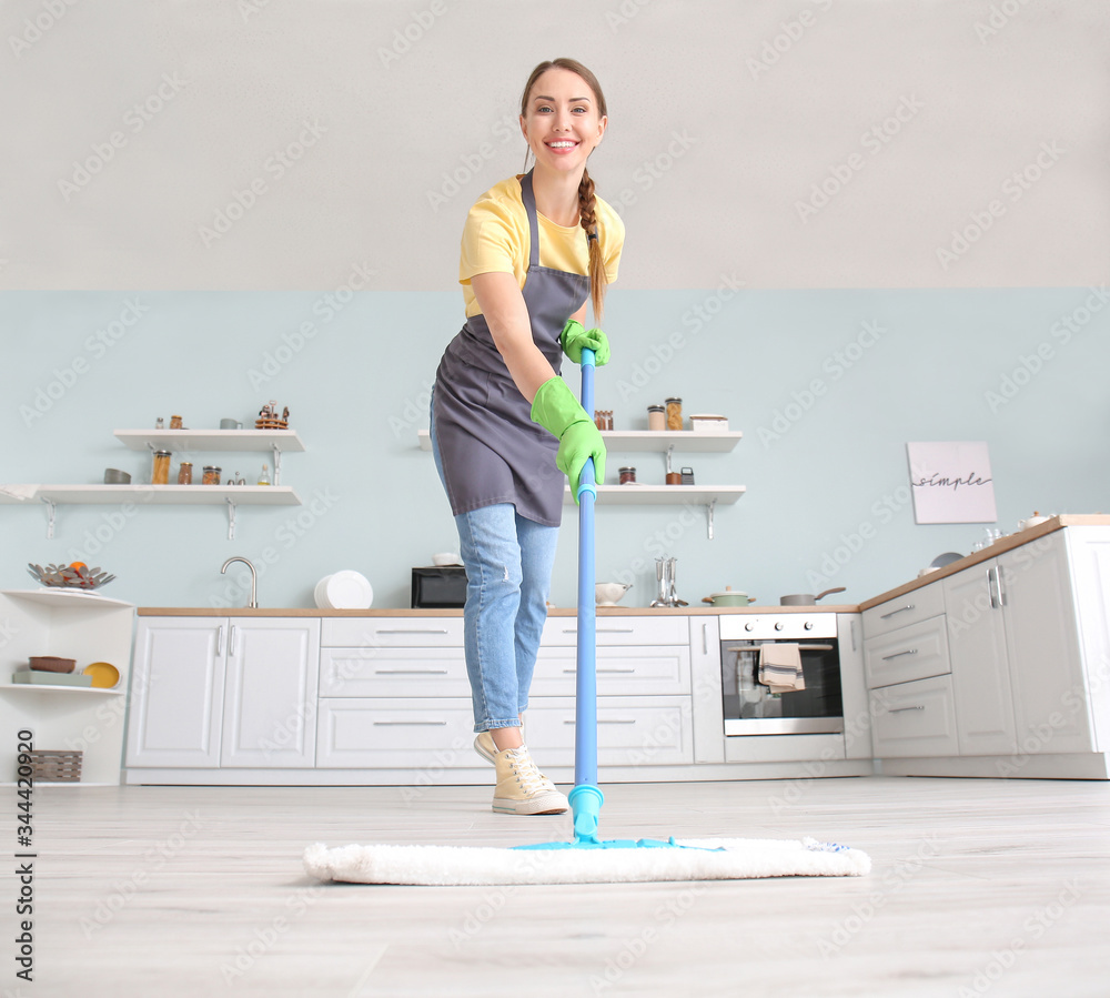 Young woman mopping floor in kitchen