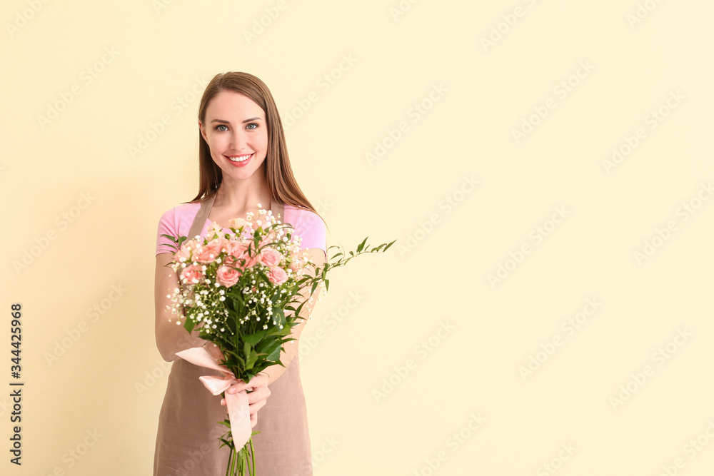 Portrait of female florist with bouquet on color background