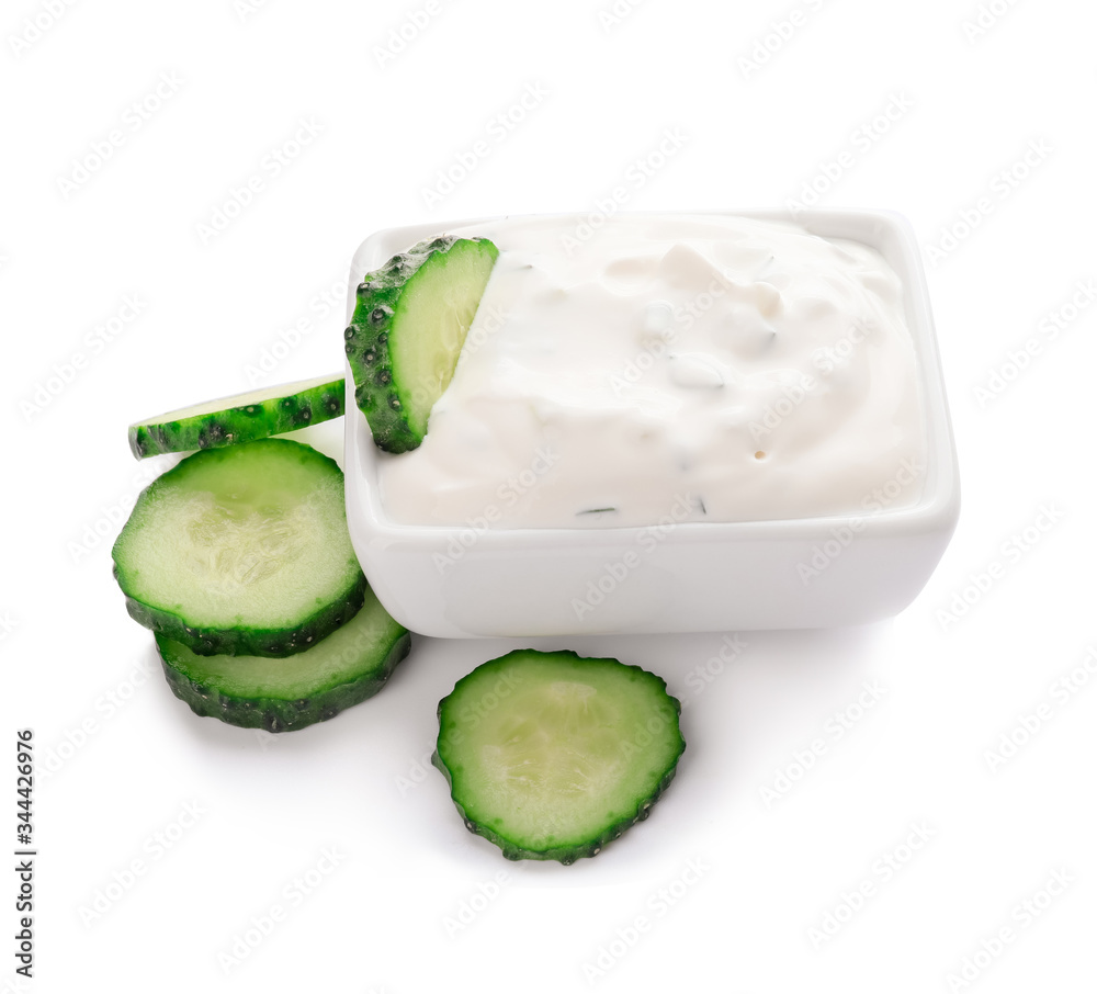 Delicious yogurt sauce with cucumber in bowl on white background