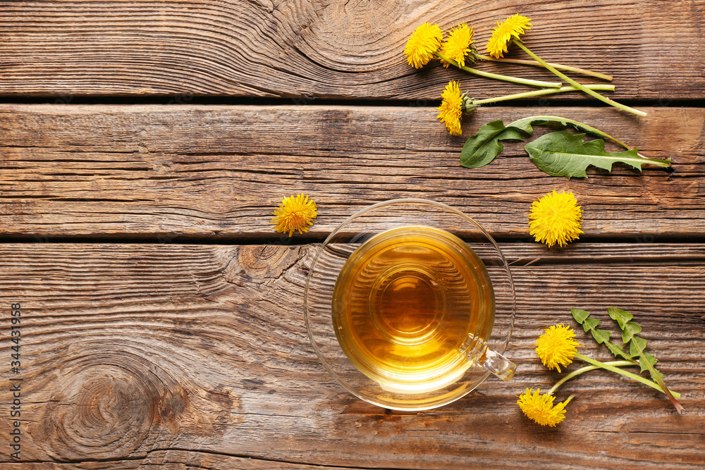 Cup of healthy dandelion tea on wooden background