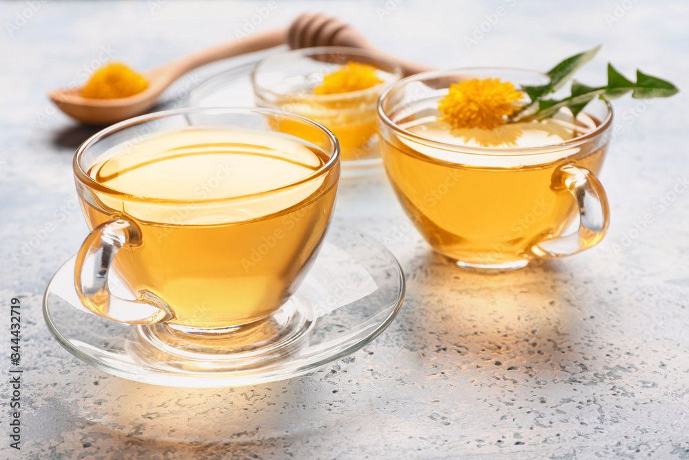 Cups of healthy dandelion tea on color background