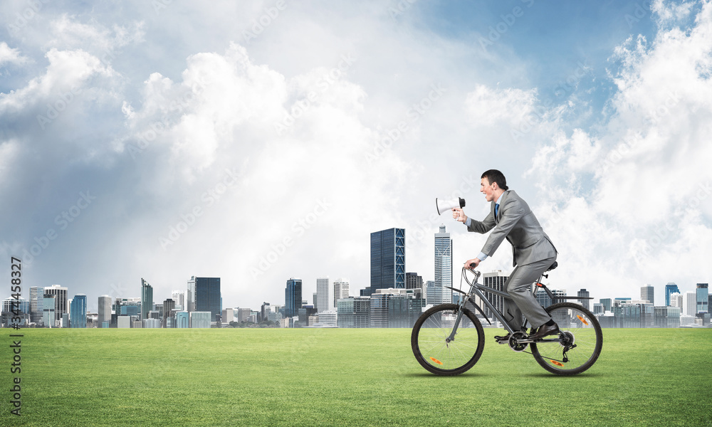 Businessman with megaphone on bike