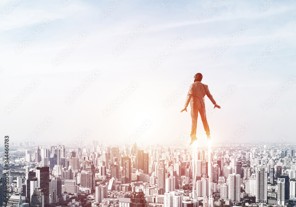 Businessman in suit and aviator hat flying in sky