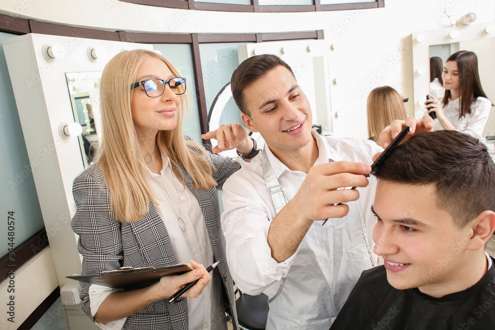 Young man with professional hairdresser and model during courses in salon