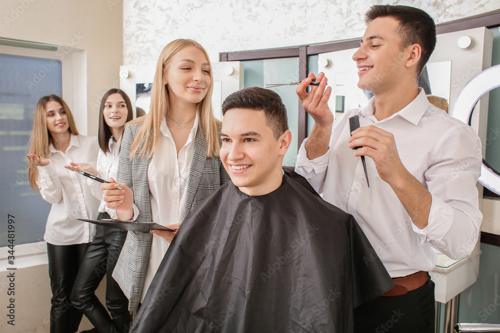 Young man with professional hairdresser and model during courses in salon