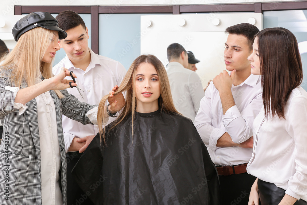 Professional hairdresser teaching young people in salon