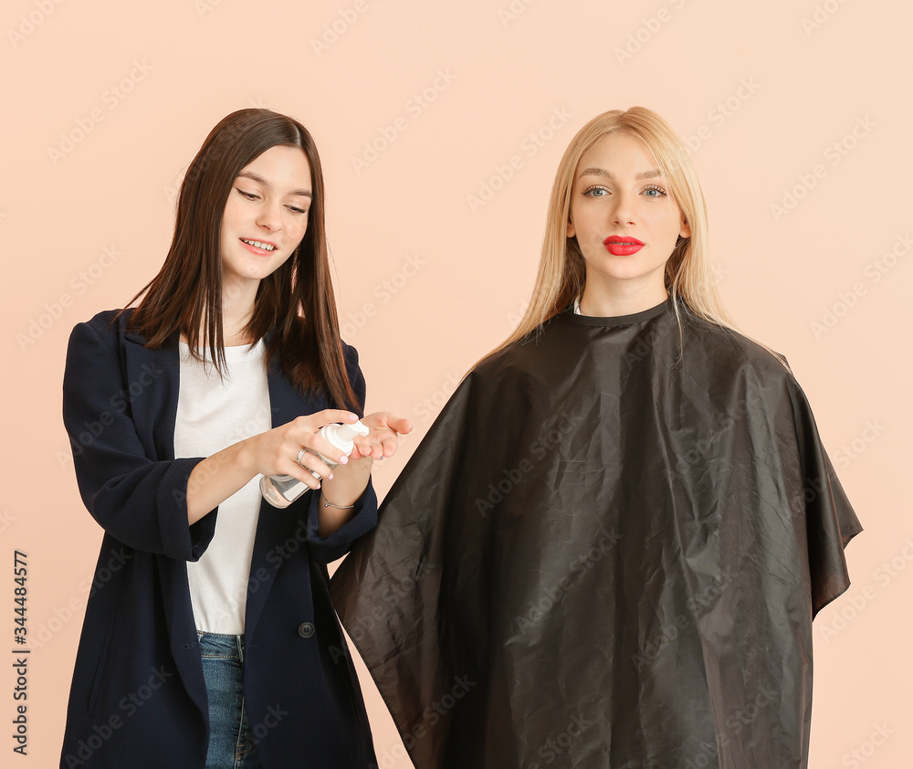 Young hairdresser working with client against color background