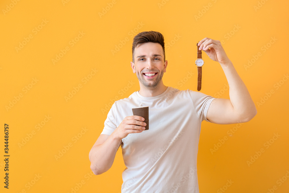 Young man with coffee and watch on color background