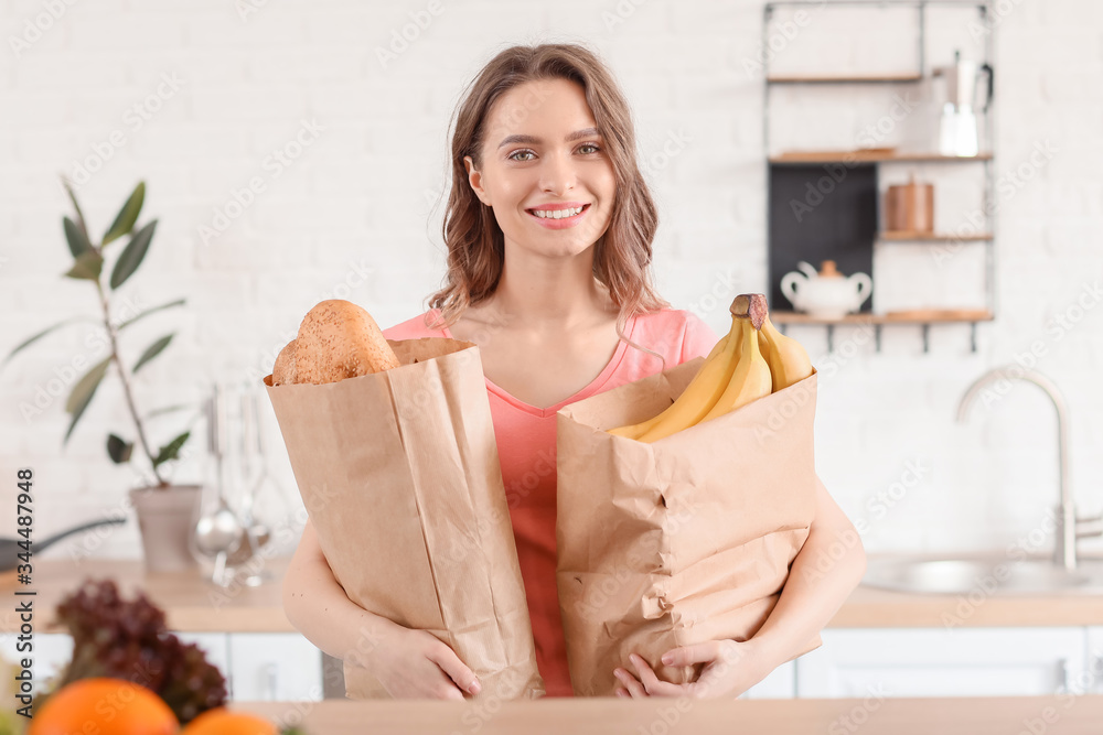 Young woman with fresh products from market at home