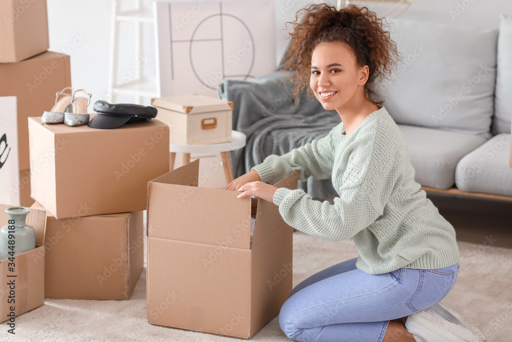 Young woman unpacking moving boxes in her new home