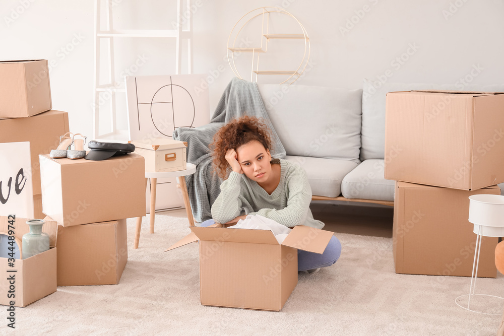 Tired young woman unpacking moving boxes in her new home