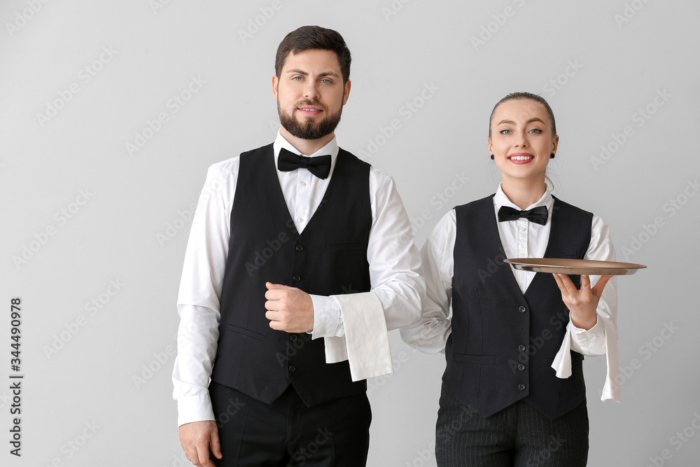 Male and female waiters on grey background