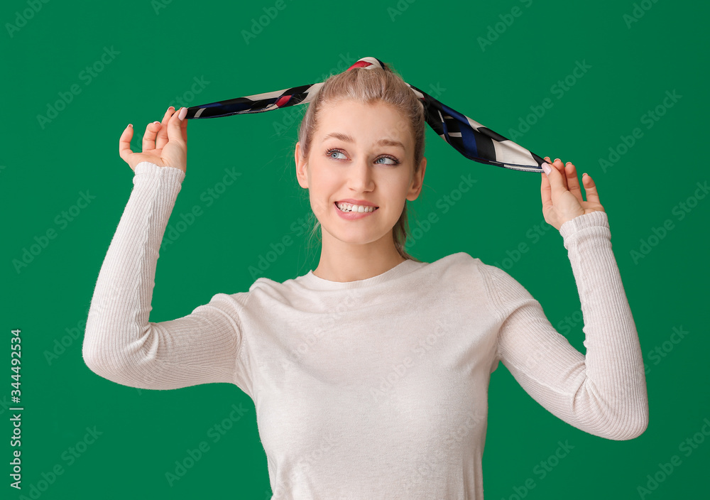 Beautiful young woman with stylish scarf on color background