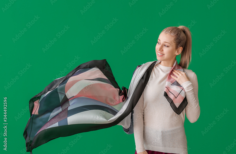 Beautiful young woman with stylish scarf on color background