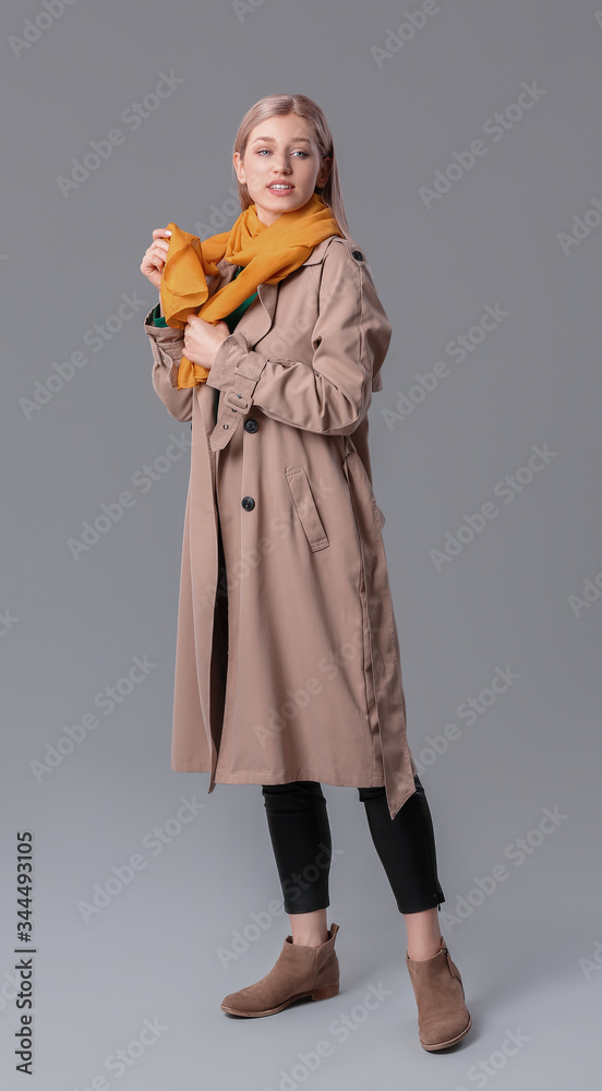 Beautiful young woman with stylish scarf on grey background