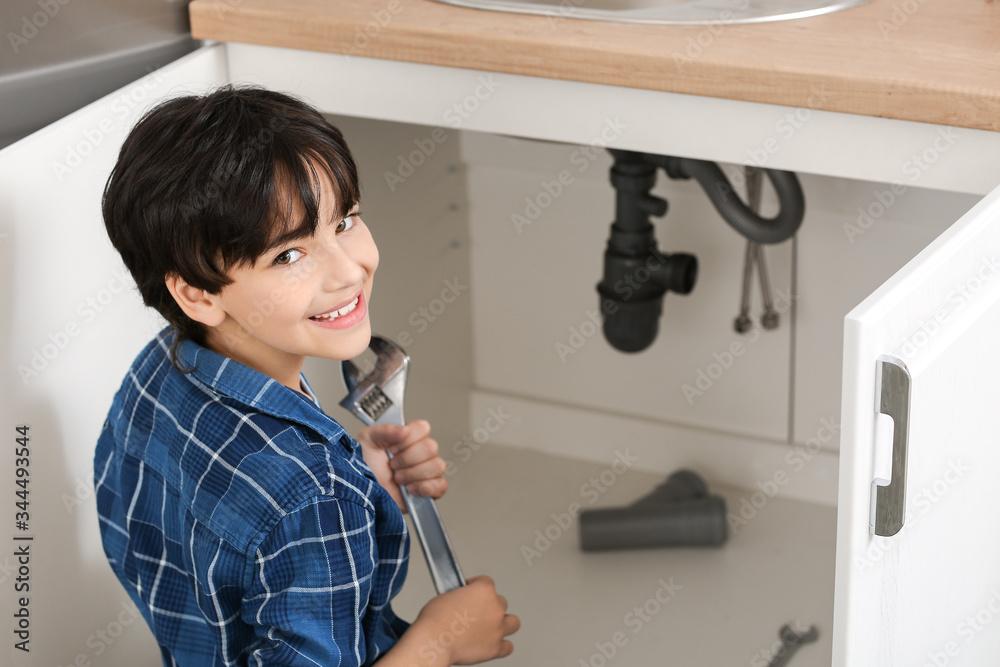 Little plumber repairing sink in kitchen