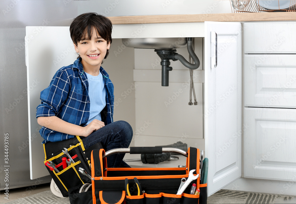 Portrait of little plumber in kitchen