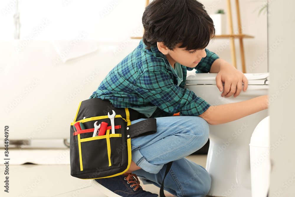 Little plumber repairing toilet bowl in restroom