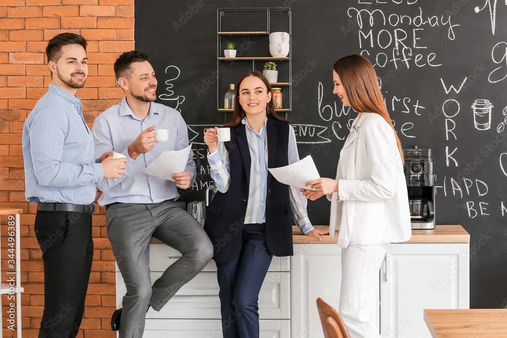 Colleagues drinking coffee in kitchen of office