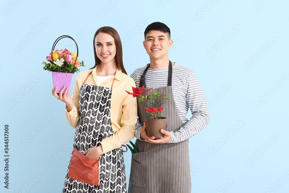 Portrait of florists with plant and bouquet on color background