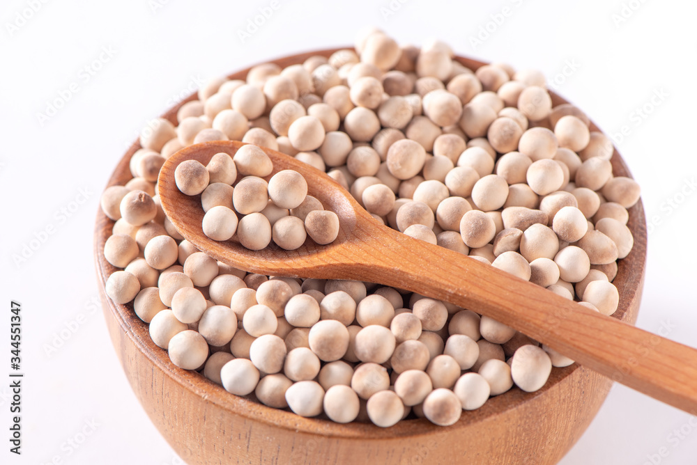 Dry raw brown tapioca pearls in a wooden bowl with spoon isolated on white background, close up, ing