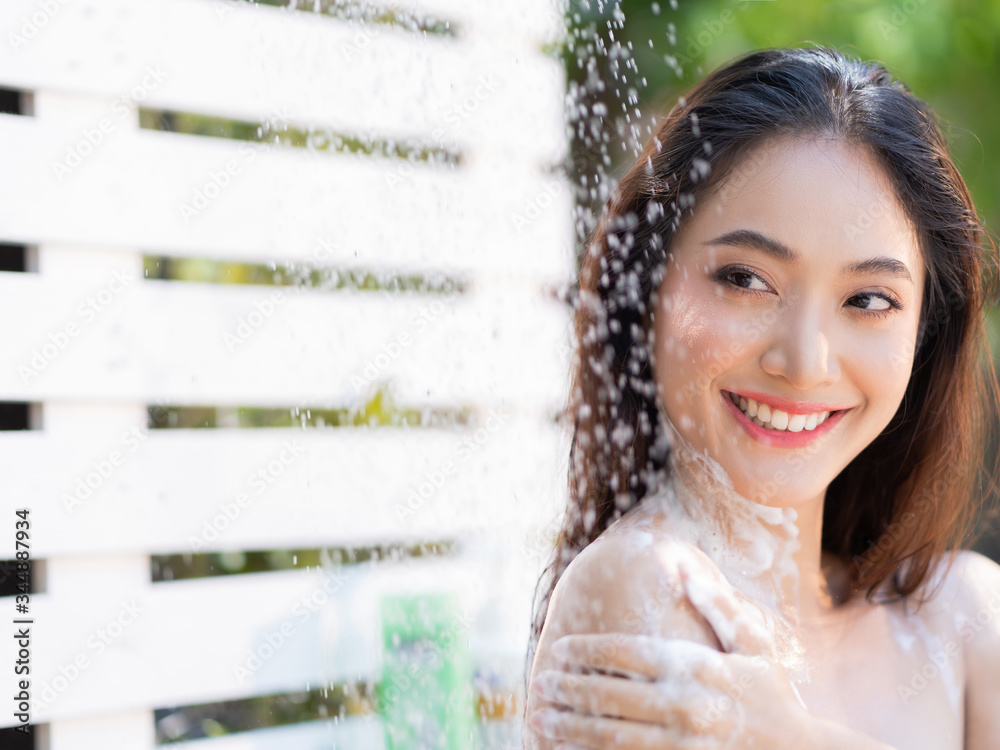 Asian woman, she uses a shower and wash hair outside. She is resting at the resort