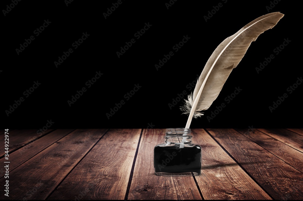 Feather quill pen and glass inkwell on desk