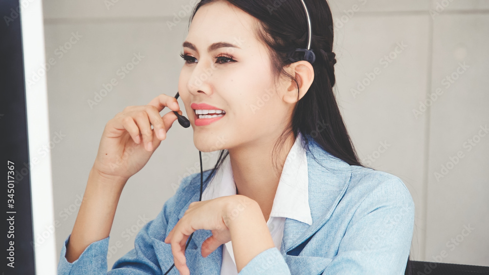 Customer support agent or call center with headset works on desktop computer while supporting the cu