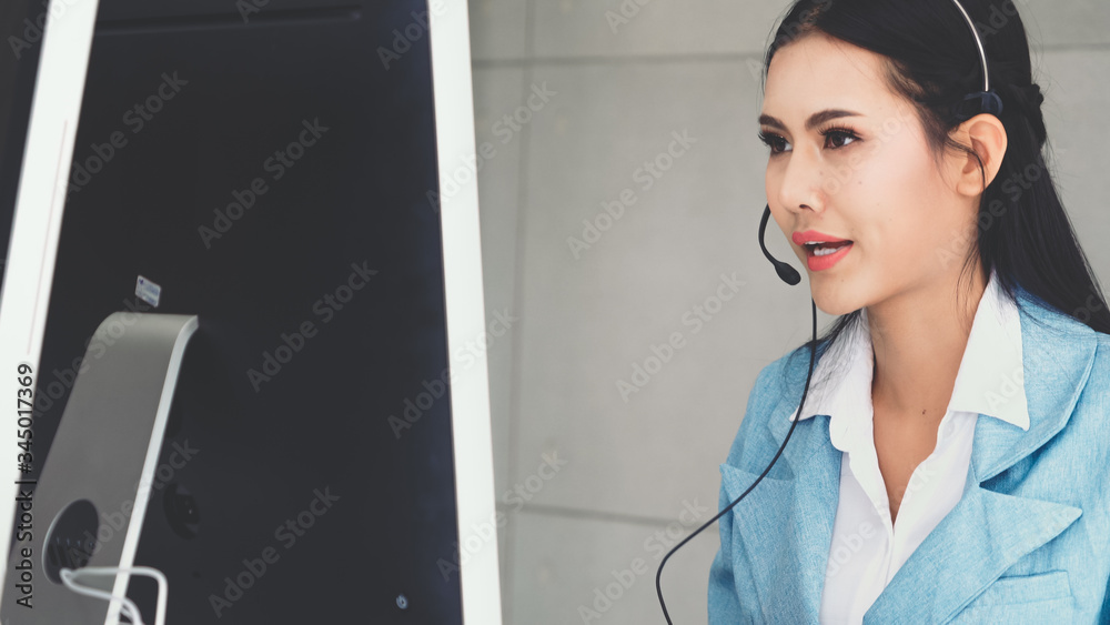 Customer support agent or call center with headset works on desktop computer while supporting the cu