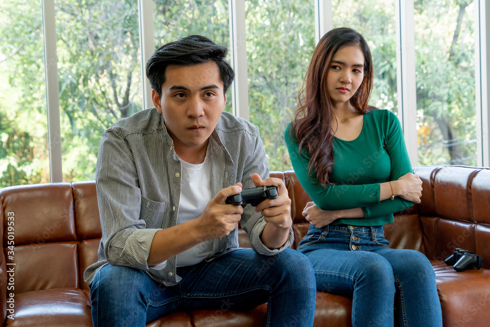 Young Asian couple suffers from computer games addiction. Family problem concept.