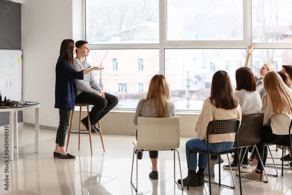 Professional hairdresser teaching young people in office