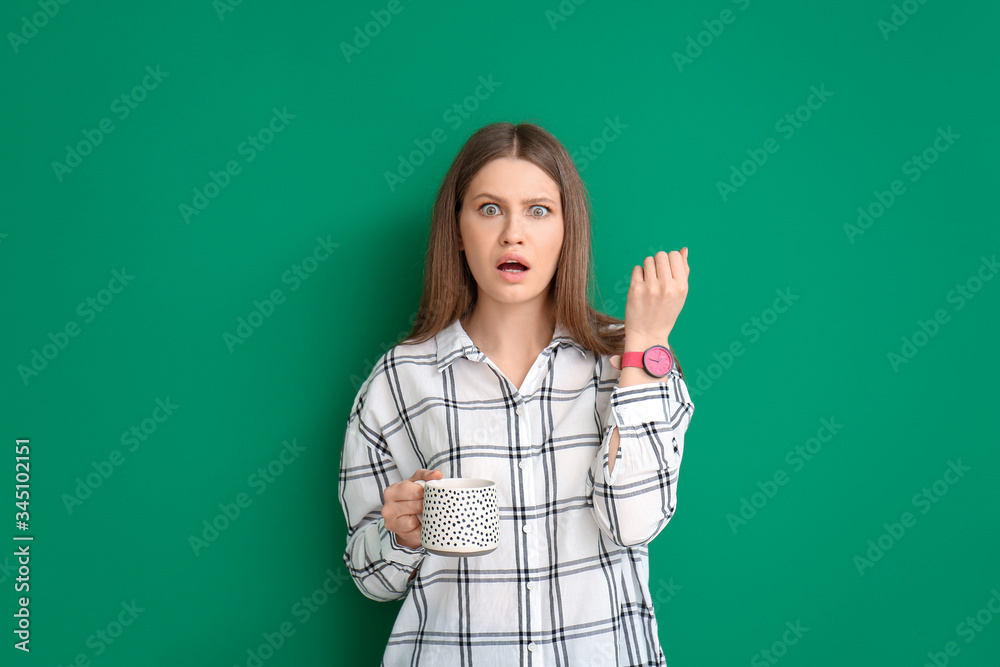 Shocked young woman with coffee on color background