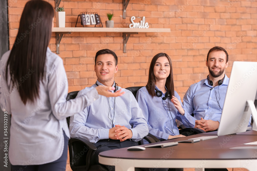 Professional technical support agent teaching young people in office