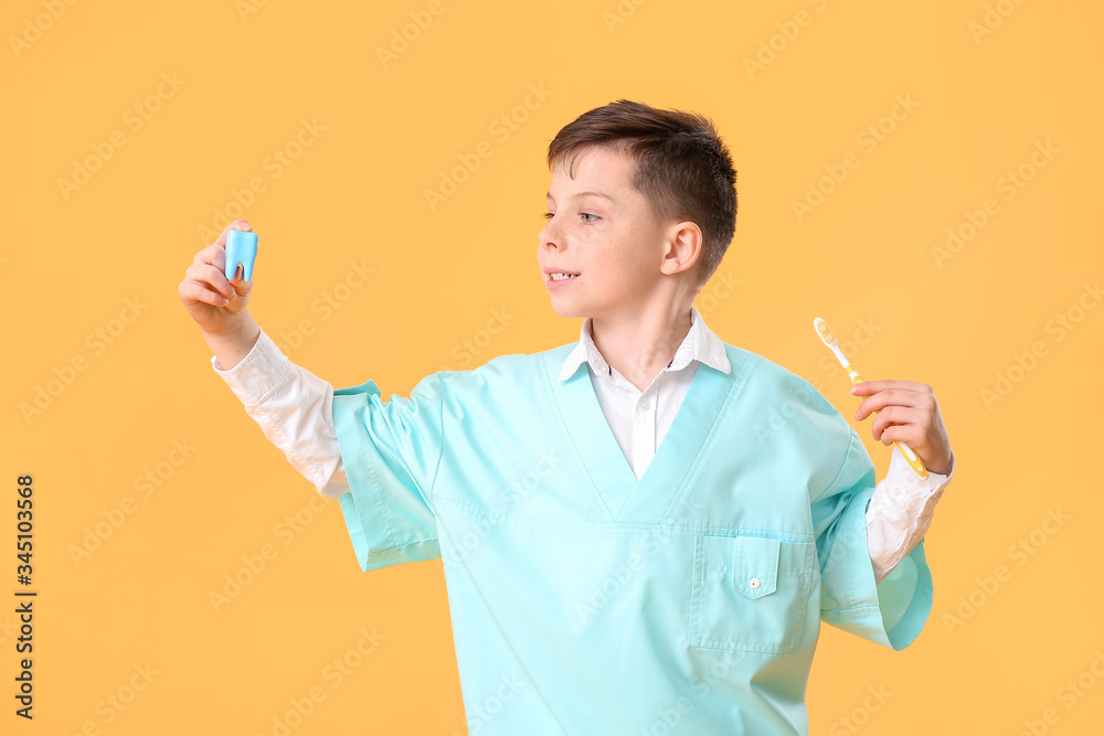 Little dentist with model of tooth and brush on color background