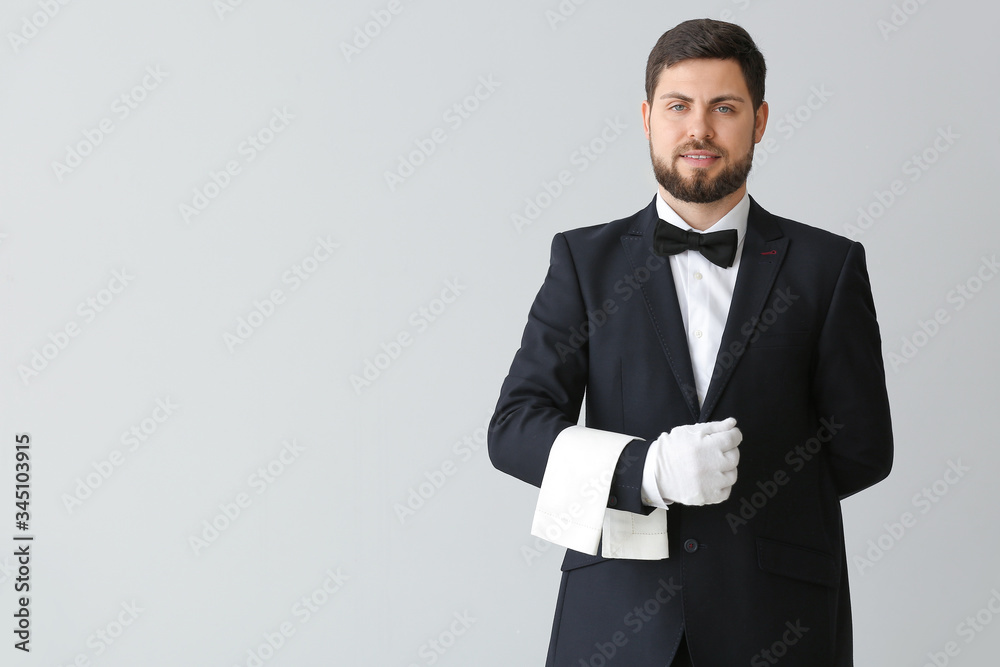 Handsome male waiter on grey background