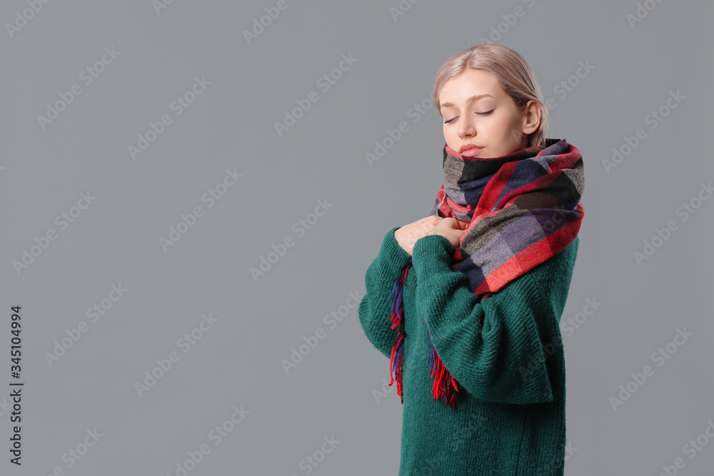 Beautiful young woman with stylish scarf on grey background