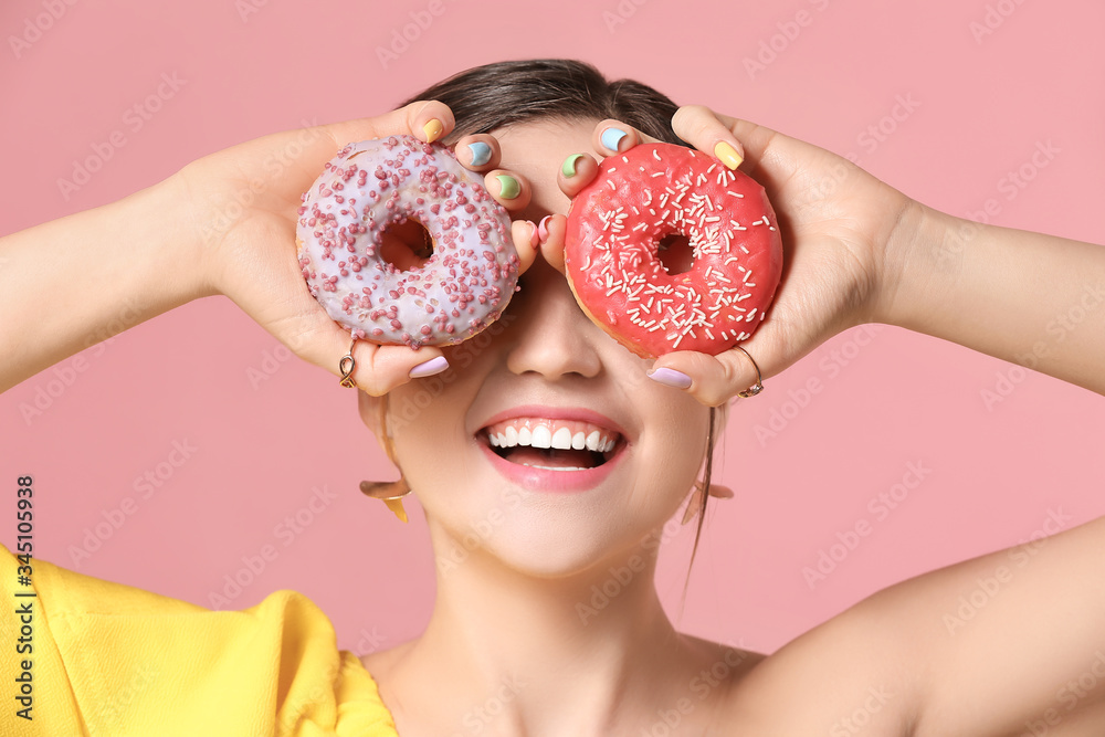 Young woman with beautiful manicure and donuts on color background