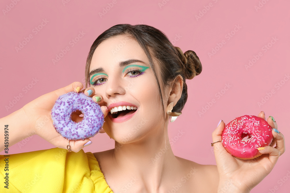 Young woman with beautiful manicure and donuts on color background