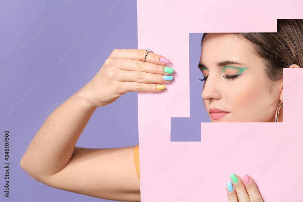 Young woman with beautiful manicure visible through cut color paper