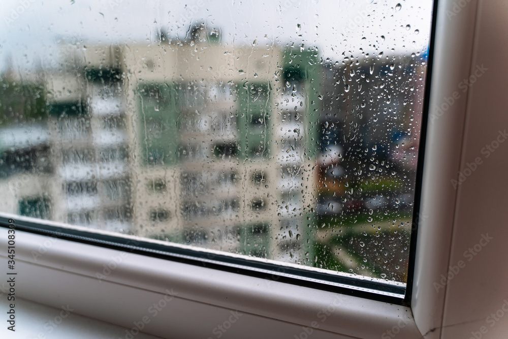 Raindrops on window glass. Selective focus. Rainy city background