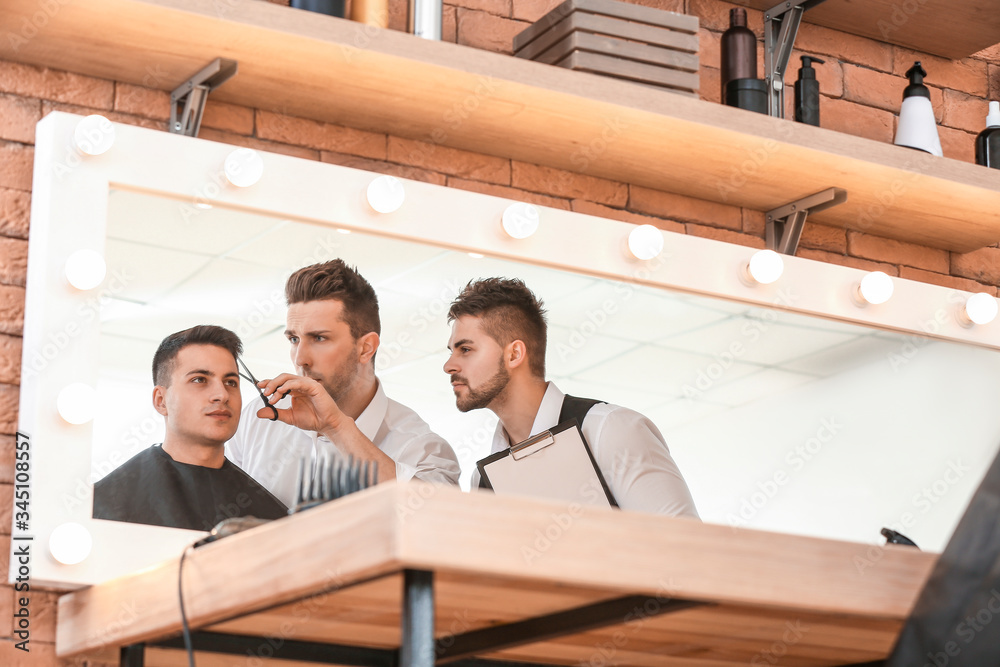 Young man with professional hairdresser and model during courses in salon