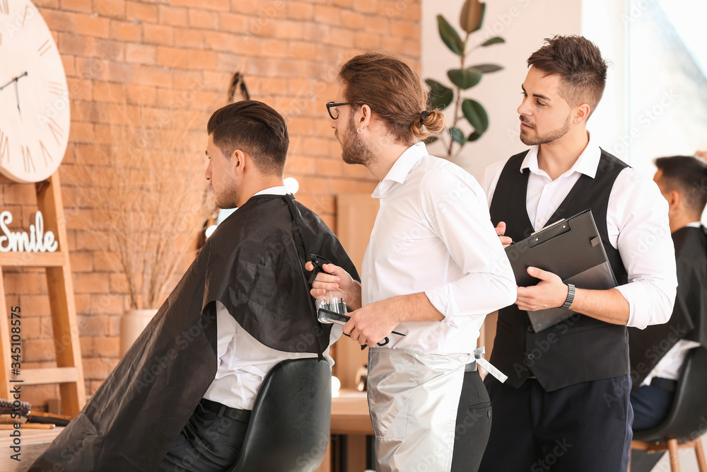 Young man with professional hairdresser and model during courses in salon