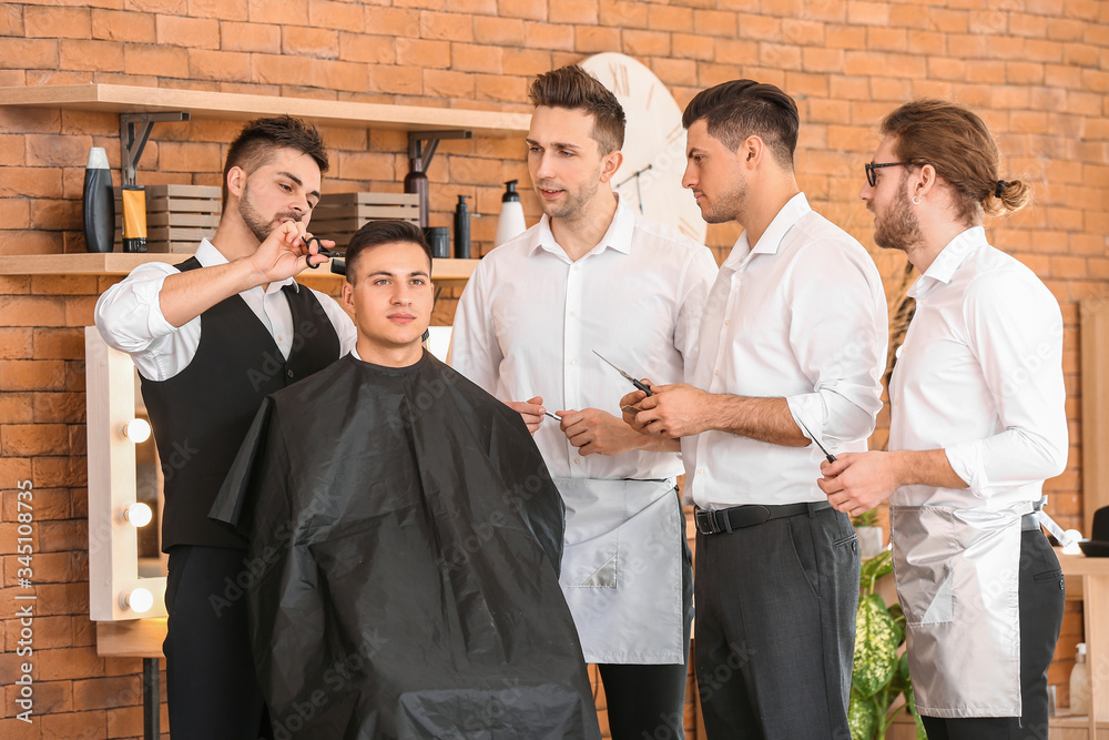 Professional hairdresser teaching young men in salon